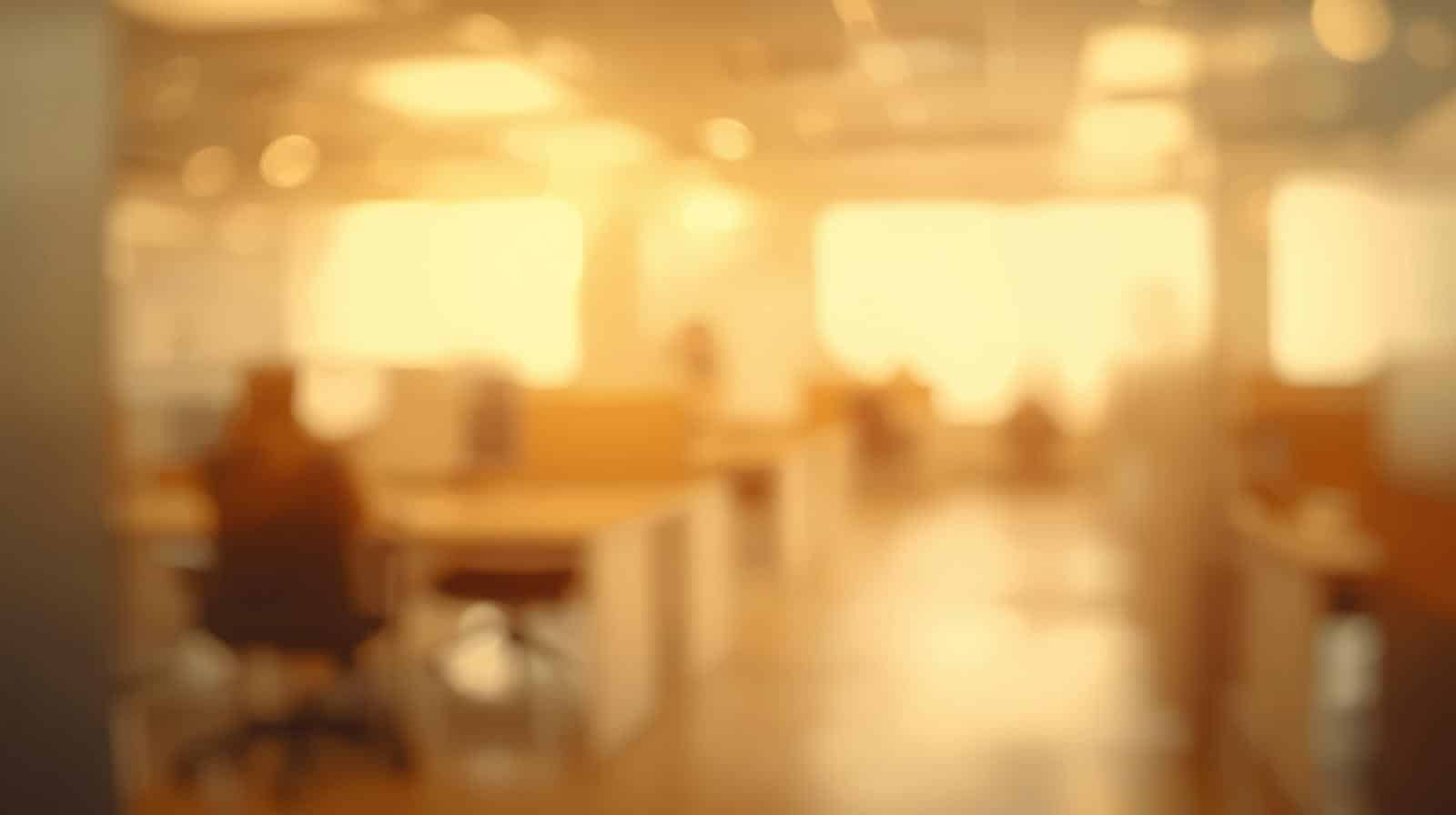 A blurred office environment in warm amber and neutral tones.